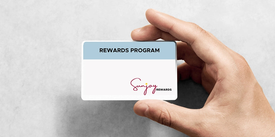 Hand holding a rewards program card with 'Sunjoy Rewards' branding on a light gray background