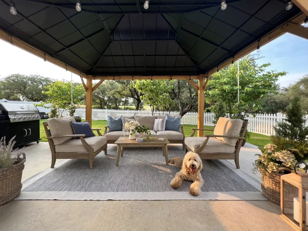 Outdoor patio with wooden gazebo, furniture, and a dog lying on the rug.