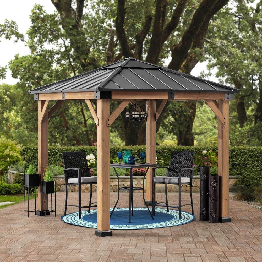 Wooden gazebo with a metal roof on a patio with outdoor furniture and plants.