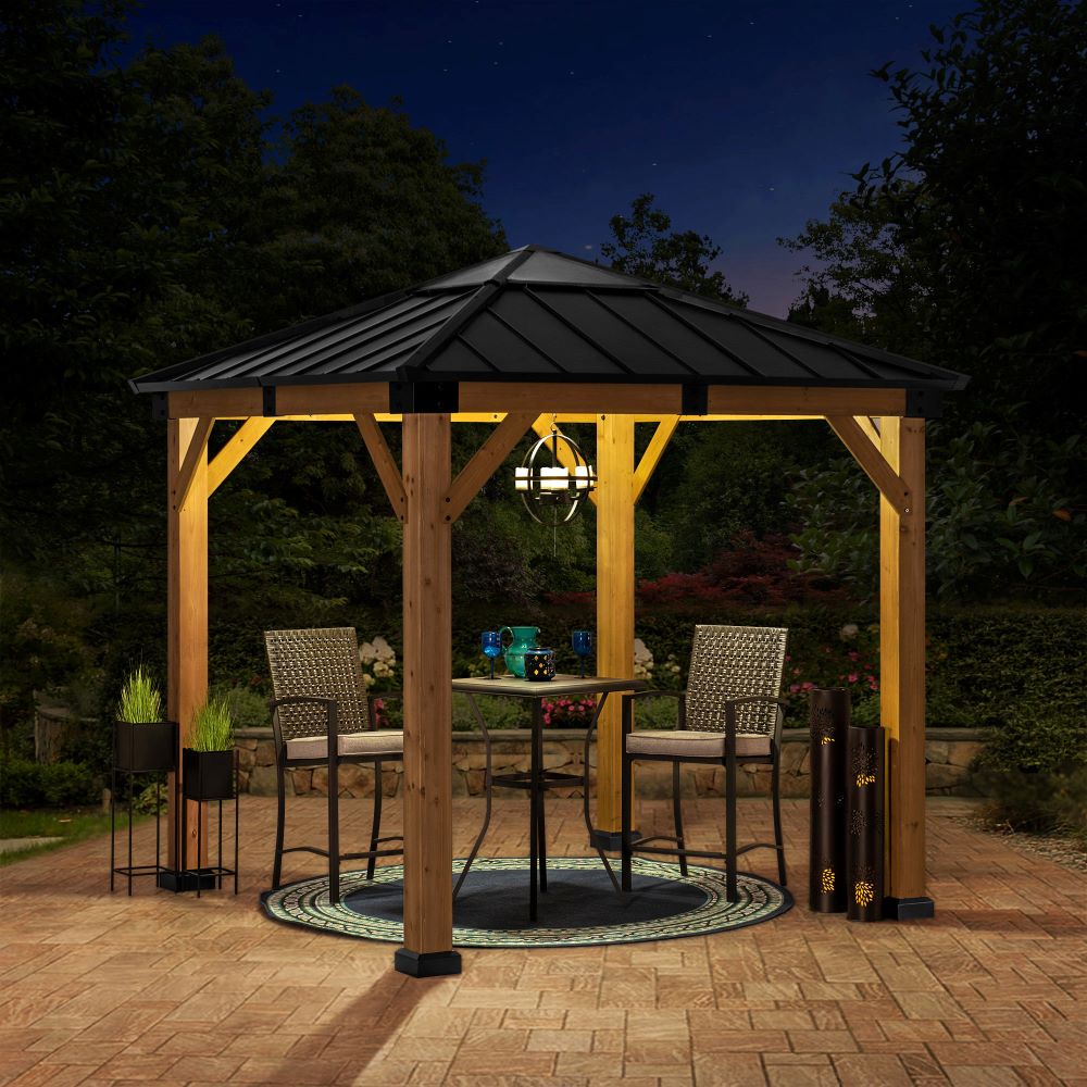 Wooden gazebo with outdoor furniture on a patio at night