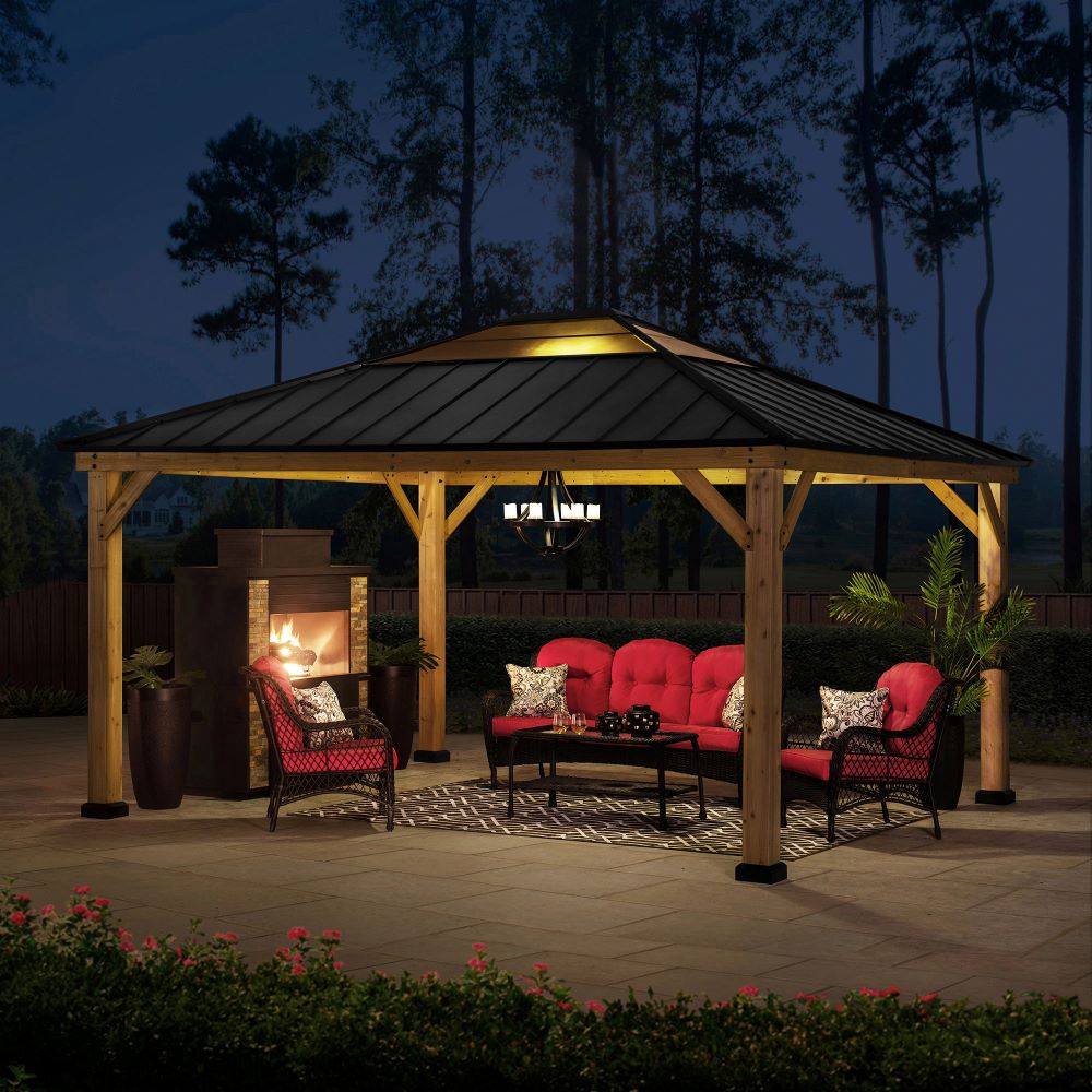 Outdoor gazebo with seating area and fireplace at night