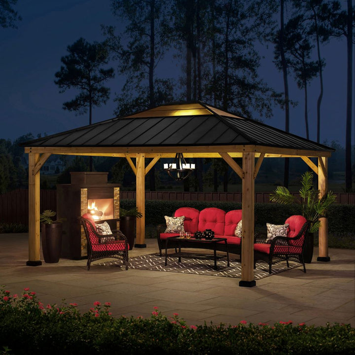 Outdoor gazebo with seating area and fireplace at night