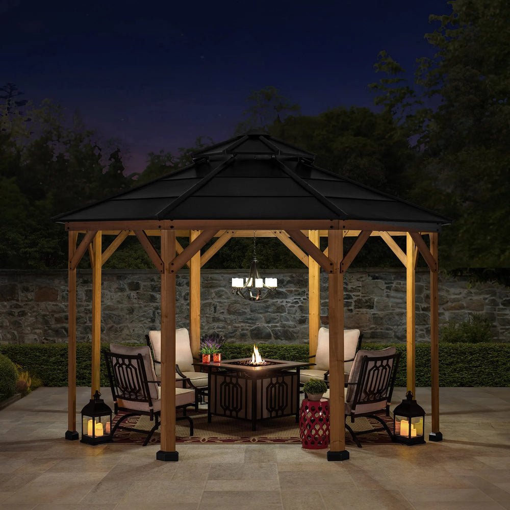 Wooden gazebo with a fire pit table and chairs at night.