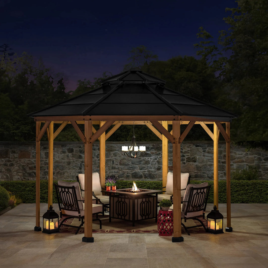 Wooden gazebo with a fire pit table and chairs at night.