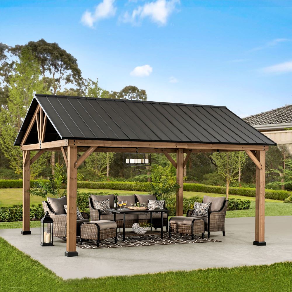 Wooden pergola with a black roof on a patio with outdoor furniture and decor.