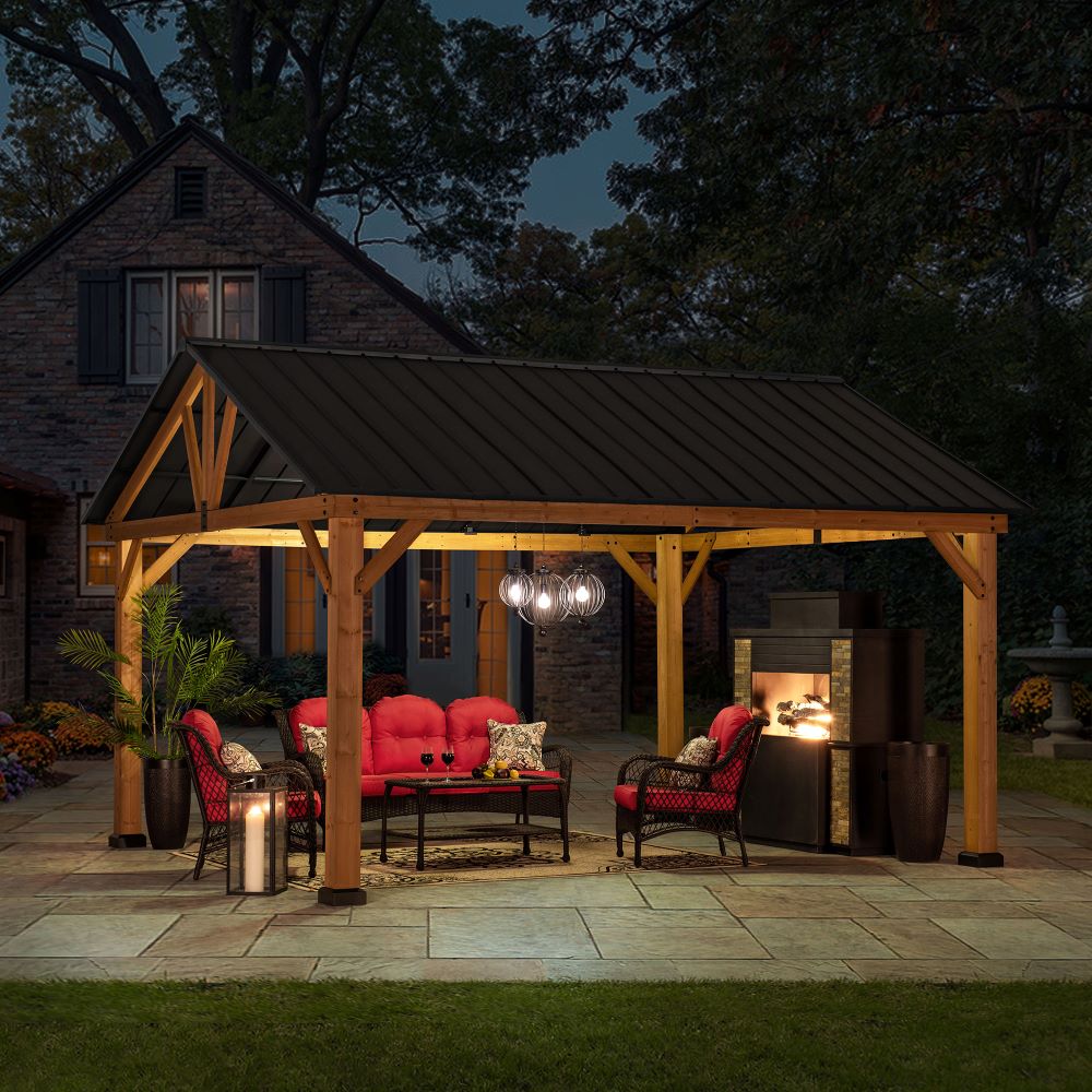 Wooden pergola with outdoor furniture and lighting at night