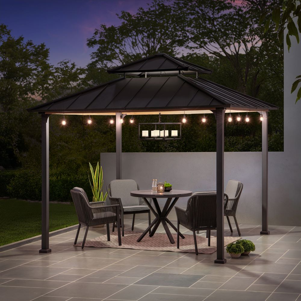 Gazebo with outdoor furniture and string lights on a patio at night.