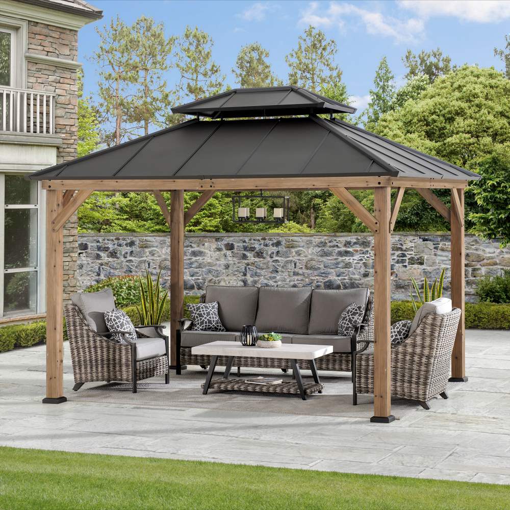 Patio with wooden gazebo, outdoor furniture, and stone wall in the background