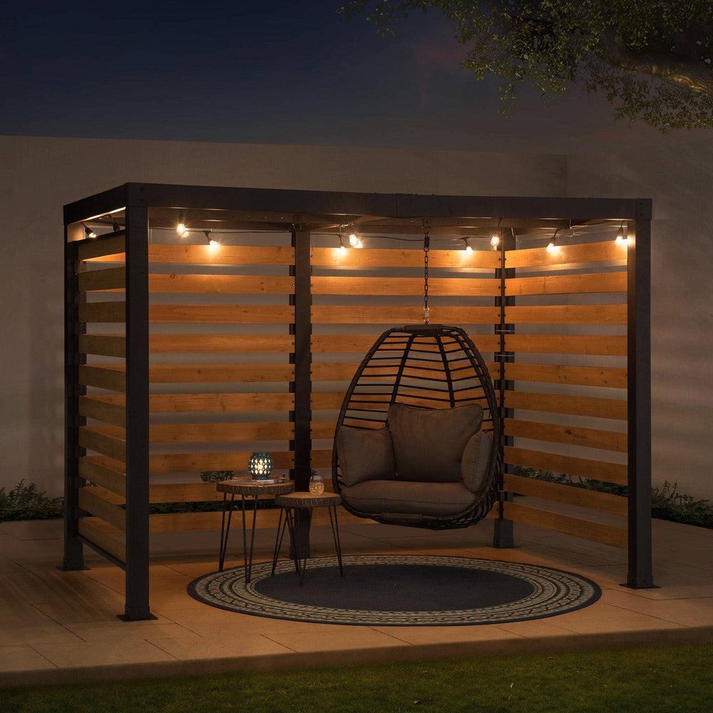 Outdoor seating area with a hanging chair, small table, and lights at night.