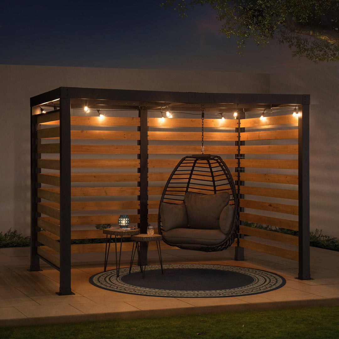 Outdoor seating area with a hanging chair, small table, and lights at night.