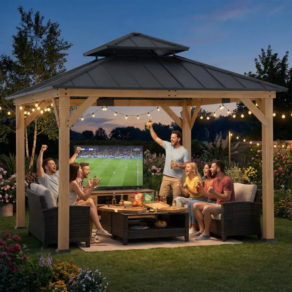 People sitting under a wooden gazebo watching a sports game on a screen, with string lights and outdoor furniture.