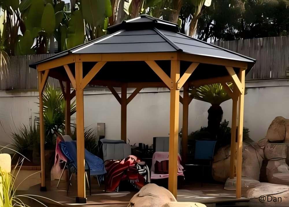 Wooden gazebo with a black roof in a backyard setting